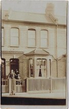 Postcard RPPC Family Dressed In Doorway Of City Home - £3.15 GBP