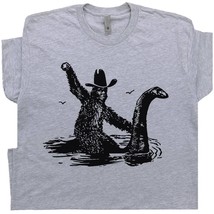 Funny Bigfoot T Shirt Sasquatch Riding Loch Ness Monster Cool Cryptid Graphic  - £15.72 GBP