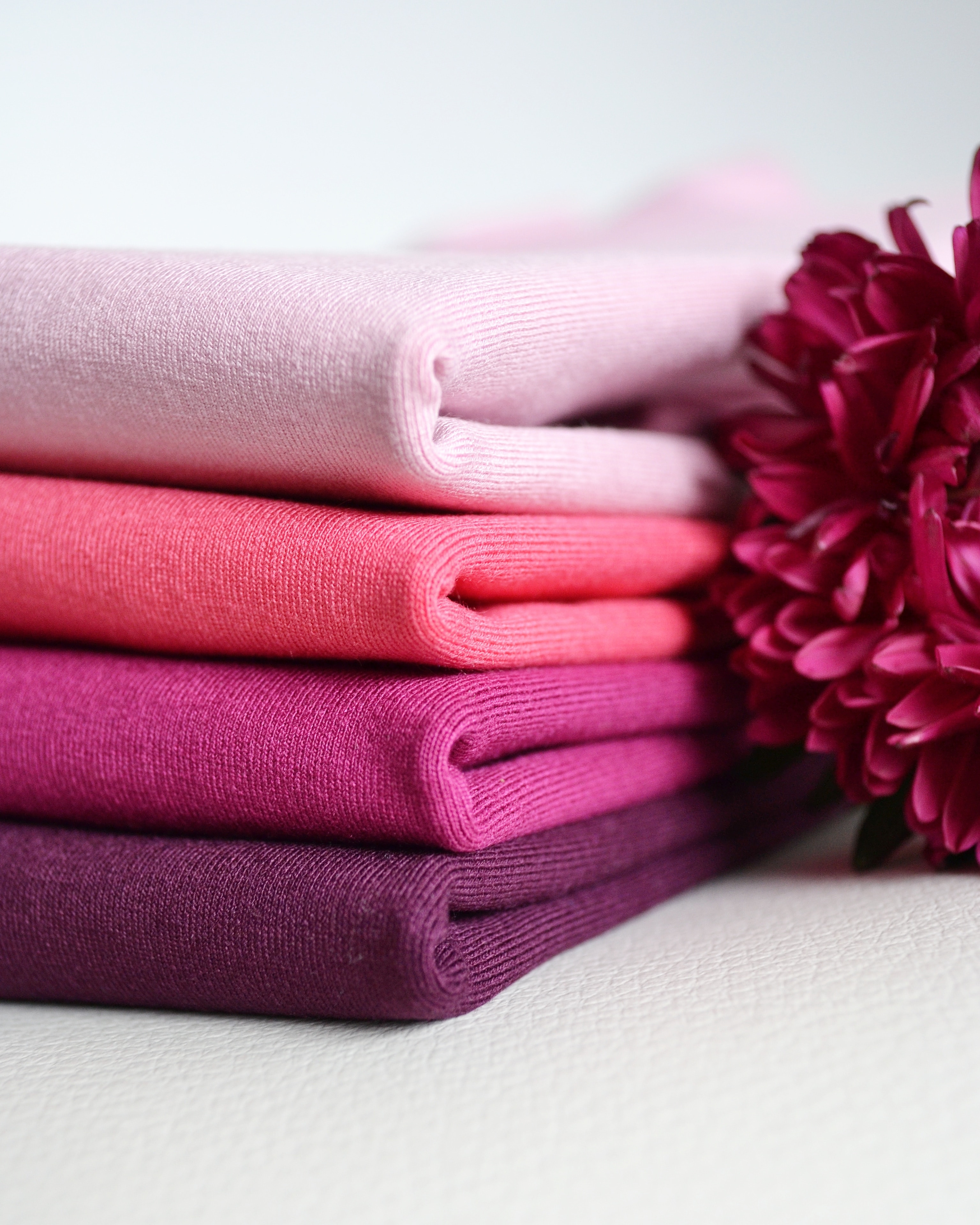 A stack of berry colored cashmere sweaters